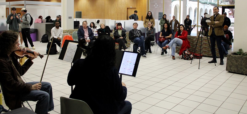 Two musicians perform for an audience in the lobby of LSU's main library